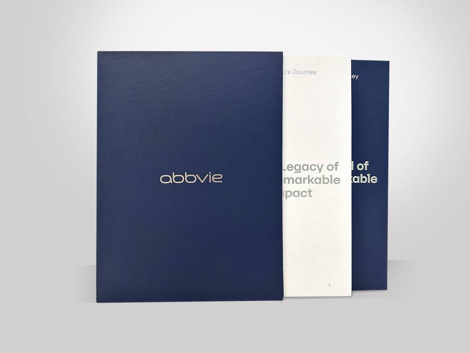 AbbVie navy and white book-style rigid boxes with foil titles by VSL Packaging