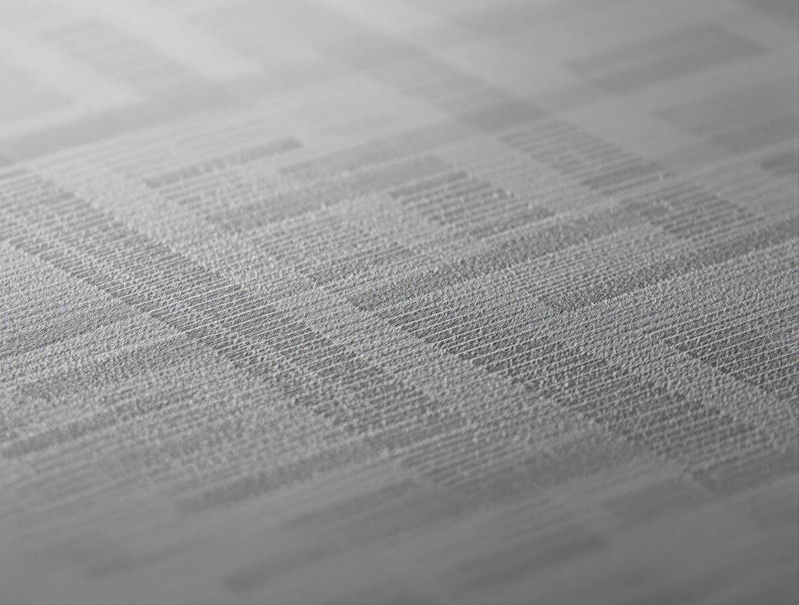 A debossed linear pattern pressed into charcoal-gray paperboard, macro texture — studio image
