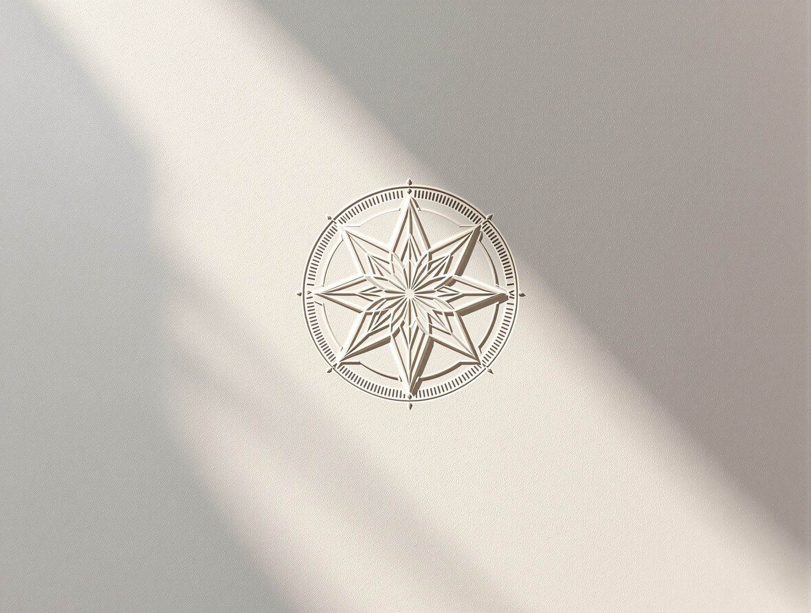 An elegant blind-embossed geometric emblem raised from thick cream cotton paper, dramatic raking light — studio image
